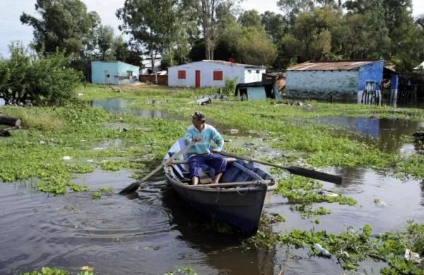 Homem se locomove de barco por uma rua de Assun&ccedil;&atilde;o, capital paraguaia (France Press)