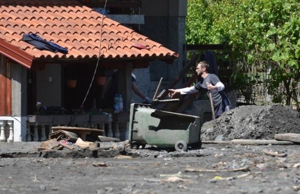 Homem retira a terra levada pelo rio, que bloqueou sua casa durante a enchente (France Press)