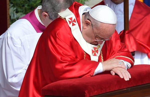 O Papa Francisco ajoelhado durante a missa do Domingo de Ramos no Vaticano  (France Press)