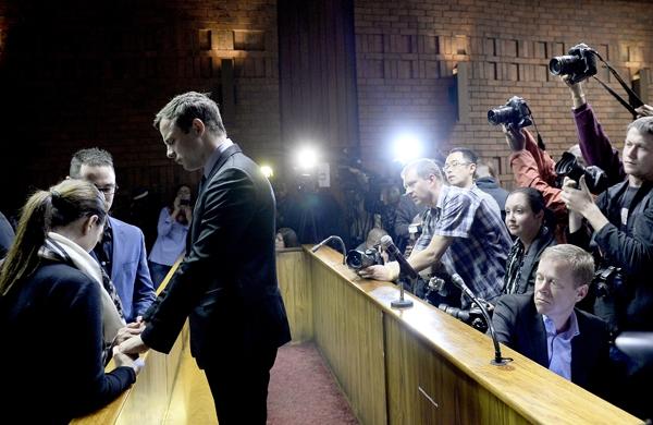 Pistorius (D) conversa com seus irmãos em um tribunal da África do Sul (France Press)