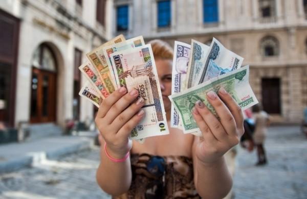 Mulher cubana mostra as duas moedas que circulavam em Cuba há 19 anos: pesos cubano e conversível  (France Press)