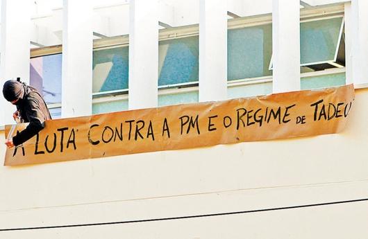 Estudante prega faixa em marquise do prédio ocupado na Unicamp: grupo é contra atuação da PM no campus, autorizada após morte em festa ( Rodrigo Zanotto/Especial para AAN)