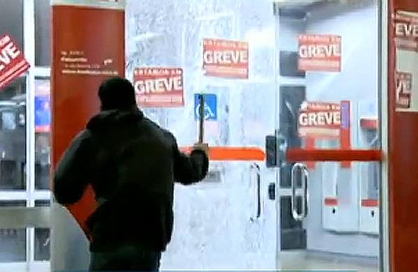 Vândalo quebra porta de vidro de agência bancária durante protesto em São Paulo (Reprodução/TV Globo)