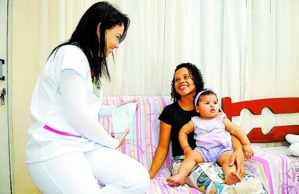 Elaine, com a filha Maria Rita no colo, durante coleta de leite materno em sua casa: ela já doou 168 litros ( Edu Fortes/AAN)