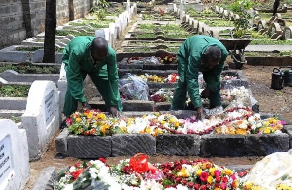 Funcionários do cemitério de Nairóbi ajeitam as flores sobre os caixões ( Divulgação)