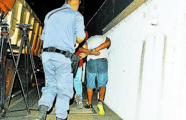 Acusados de tráfico presos na ação são conduzidos por policial militar ( Dominique Torquato/AAN)