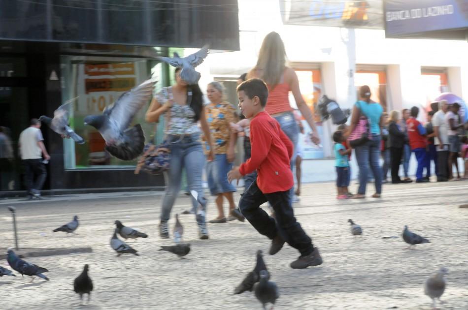 Menino brinca com pombos no Largo do Rosário, espaço conhecido por concentrar aves: proibição é rejeitada por alguns frequentadores (Edu Fortes/AAN)