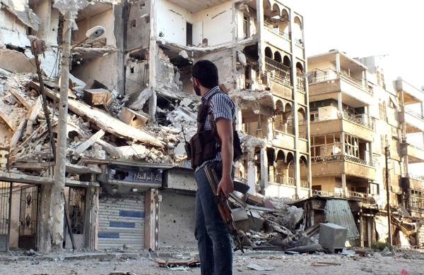 Rebelde sírio observa prédio destruído por bombardeio em Homs (France Press)