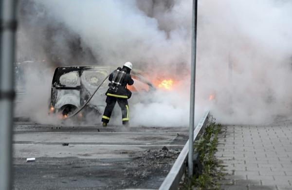Bombeiro luta contra o fogo em veículo incendiado por protestantes em Estocolmo, na Suécia (France Press)