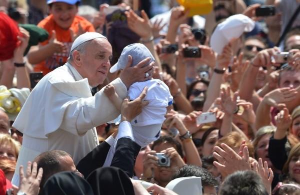 Papa Francisco carrega um bebê após a oração do Regina Coeli, na praça do Vaticano (France Press)